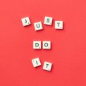 Motivational phrase 'Just Do It' spelled with Scrabble letters on a red background.