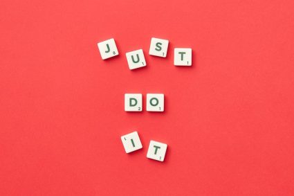 Motivational phrase 'Just Do It' spelled with Scrabble letters on a red background.