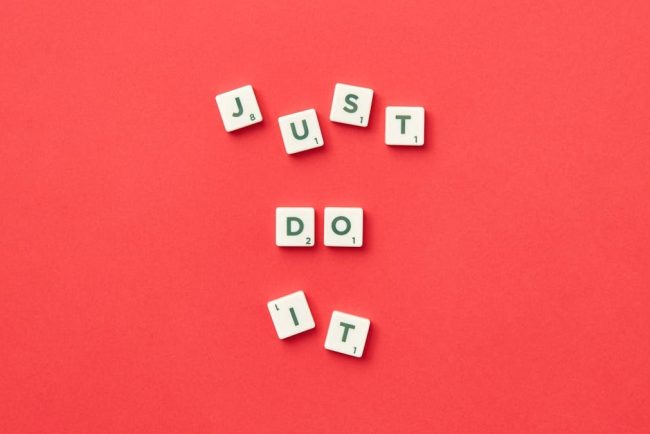 Motivational phrase 'Just Do It' spelled with Scrabble letters on a red background.