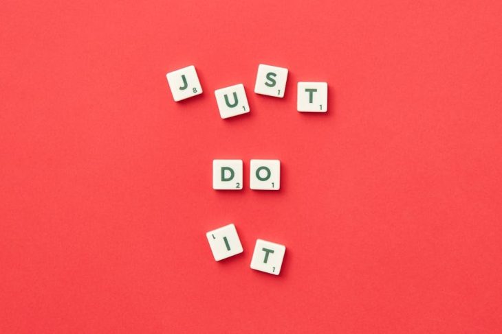 Motivational phrase 'Just Do It' spelled with Scrabble letters on a red background.