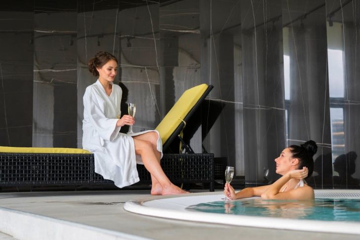 Two women enjoy a luxurious poolside moment with champagne, embodying relaxation and leisure.